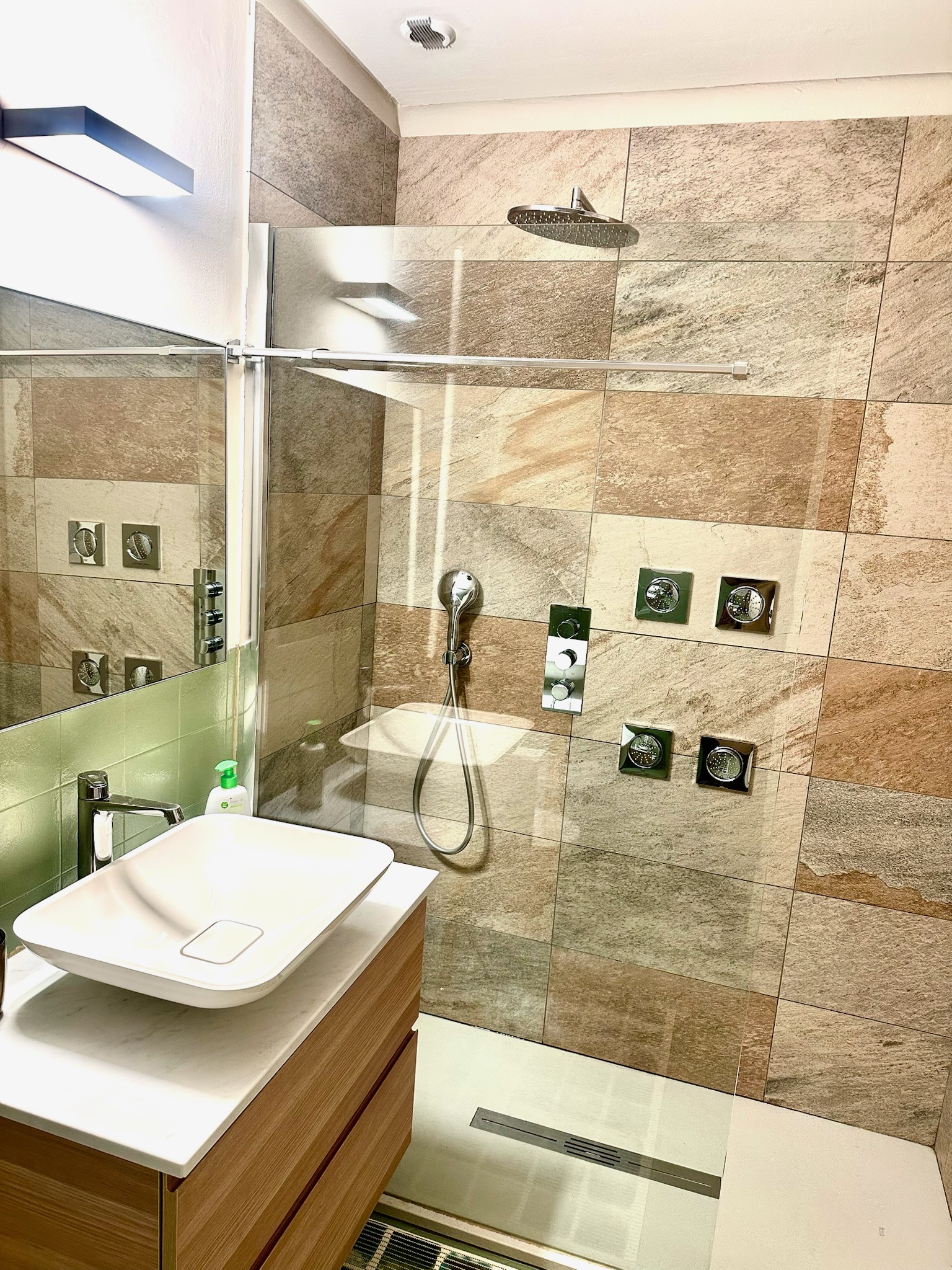 Walk-in shower with rainfall head, body jets, and natural stone tiles