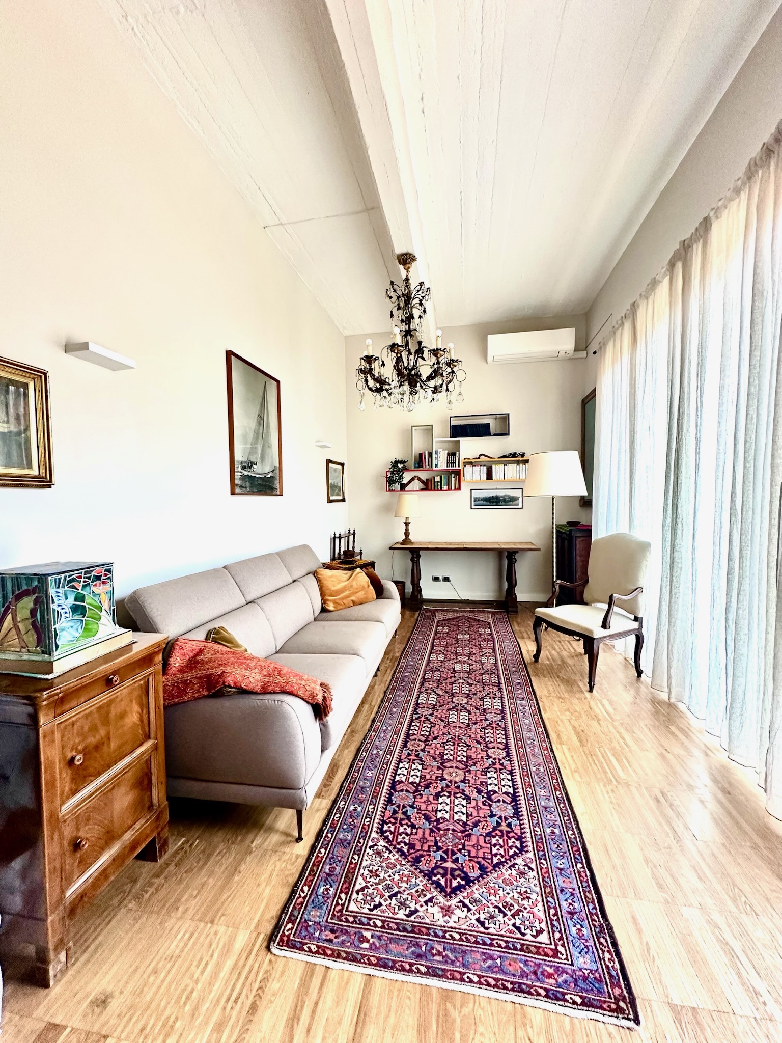 Open-plan living room with crystal chandelier, Persian rug, and vintage furnishings